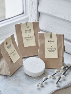 three brown paper bags sitting on top of a table next to a bowl and spoon