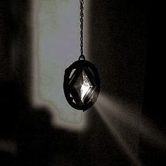 a black and white photo of a light bulb hanging from a chain in the dark