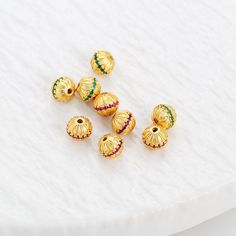 five gold - plated beads with multicolored stones on a white tablecloth