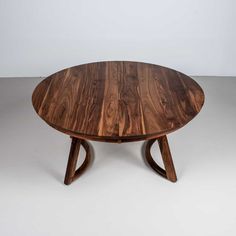 an oval wooden table with two crossed legs and a circular wood top, on a white background