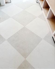 a white tiled floor in a kitchen next to a refrigerator and cabinets with shelves on each side