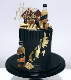 a black and gold birthday cake with wine bottles