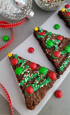 two pieces of christmas brownies on top of paper with sprinkles and candy