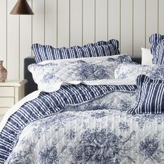 a bed with blue and white comforters in a bedroom next to a night stand