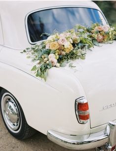 an old white car with flowers on the back