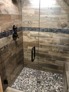 a walk in shower sitting next to a tiled wall and floor covered in brown tile