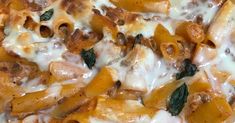 a close up view of some pasta with cheese and spinach leaves on the top