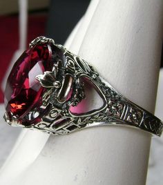 Simulated Red Ruby Ring Description Princess Design#29 MADE TO ORDER Inspired by Georgian and Victorian era filigree designs, I now offer this stunning reproduction in sterling silver. This fabulous ring is set with a 6ct flawless Simulated Red Ruby. The brilliant full cut high-quality ruby red gem is 13mm (1/2th of an inch) in diameter. The inside of the band is marked 925. Notice the beautiful intricate leaf prongs and flower crowns like the design of the silver filigree setting and band. This Victorian Princess, Leaf Filigree, Red Ruby Ring, Rubin Ring, Princess Design, Order Design, Flower Crowns, Red Band, Filigree Design