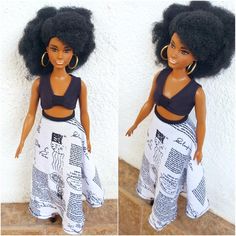 the doll is wearing a skirt with newspaper pages on it and has big hoop earrings