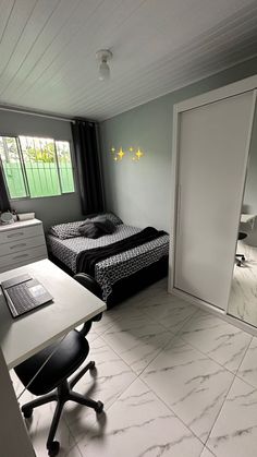 a room with a bed, desk and chair in it next to a door that leads to a bedroom