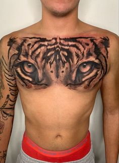 a man's chest with a tiger tattoo on it and his eyes are open