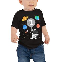 a baby boy wearing an astronaut shirt with the number one on it's chest