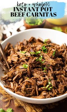 a white bowl filled with shredded beef and garnished with parsley