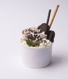 an ice cream sundae with oreo cookies and whipped cream in a white cup