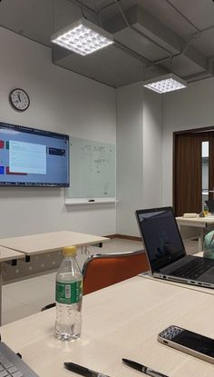 a laptop computer sitting on top of a table in front of a whiteboard and monitor