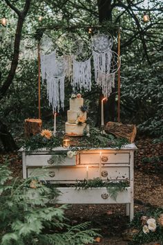 an old dresser is decorated with greenery and candles for a rustic wedding cake table