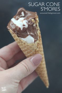 someone is holding an ice cream cone with chocolate and marshmallows in it