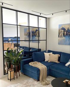 a living room filled with blue couches next to a large glass window covered wall