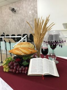 an open book on a table with grapes, bread and wine glasses next to it