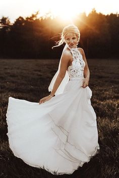 a woman in a white dress is standing in the grass with her hands on her hips