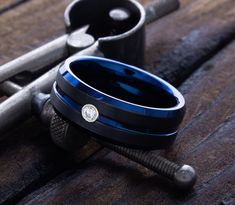 two black and blue wedding bands sitting next to each other on top of a wooden table