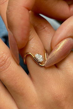 a close up of a person's hand holding a ring with a diamond on it