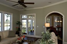 a living room filled with furniture and windows next to a table covered in flowers on top of a wooden floor