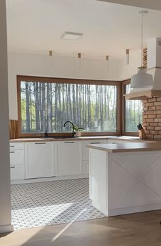 a kitchen with white cabinets and an island in front of a window that looks out onto the woods