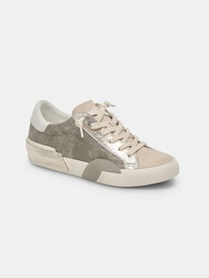 The best-selling Zinna Sneaker in Granite Metallic, a stylish fusion of comfort and trend. This sneaker features a sleek metallic color that adds a touch of sophistication to your casual style. The suede toe detailing not only enhances the overall aesthetic but also provides a subtle textural contrast. Step out in modern elegance with these sneakers, perfect for versatile and fashion-forward looks. SIZE & FIT Fit is true to size DETAILS Leather Upper Rubber Outsole Textile Lining Synthetic Sock Zina Sneakers, Shoe Boot Sandals, Perforated Leather, Trendy Sneakers, Classic Sneakers, Light Blue Denim, Suede Sneakers, Bold Prints, Gold Leather