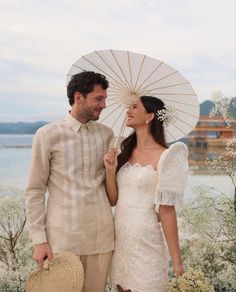 a man and woman standing next to each other holding an umbrella