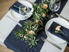 the table is set with white plates and silverware, blue napkins, and flowers