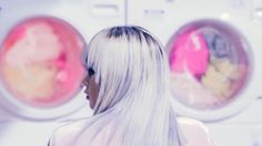 a woman with long white hair standing in front of a dryer