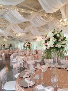 a banquet hall with tables and chairs covered in white draping, decorated with flowers