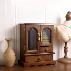 a wooden cabinet sitting on top of a table next to a mannequin's dummy