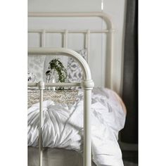 a bed with white sheets, pillows and a basket on the headboard in front of it