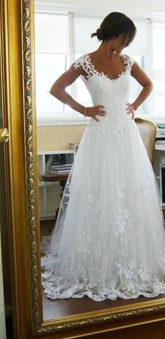 a woman standing in front of a mirror wearing a wedding dress