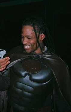 a man dressed up as a batman using his cell phone while wearing a costume with dreadlocks