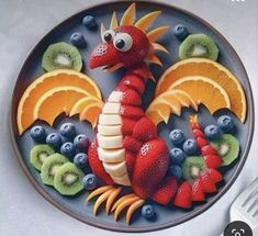 a plate that has fruit on it and a dragon made out of kiwis