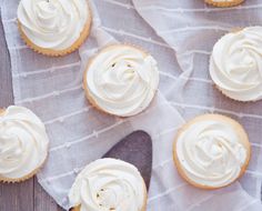 cupcakes with white frosting sitting on top of a table