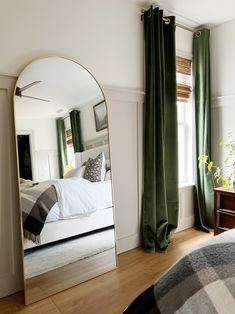 a bedroom with a large mirror on the wall and a bed in the corner next to it