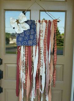 an american flag hanging on the front door with ribbons and bows attached to it,