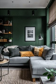 a living room with green walls and grey couches in it, along with a rug on the floor