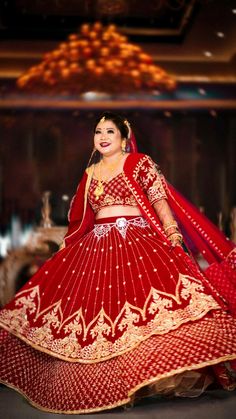 a woman in a red and gold bridal gown is posing for the camera with her hands on her hips