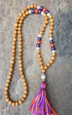 I created this boho chic tassel necklace using Light brown wood grain beads (8mm) spaced by Czech glass gold seed beads purple,orange & white celestial glass pearl beads (8mm) A white pearl bead (10mm) encased by sparkly rondelle beads, leads to a handmade, 100% cotton tassel charm. I used varying shades of purple, orange & white This beaded necklace measure 32 inches16 inches each side. Total hanging length from nape of neck to end of tassel is 20 inches. Other styles available 😀😀 Oth Bohemian Purple Necklace With Wooden Beads, Bohemian Tassel Necklace With Wooden Beads For Gift, Orange Bohemian Jewelry With 8mm Beads, Bohemian Wooden Beads Tassel Necklace Gift, Orange Amp, Necklace Orange, Brown Necklace, Purple Necklace, Long Beaded Necklace