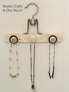 a wooden hanger with several different necklaces hanging from it's hooks on a white wall