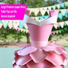 a pink paper dress sitting on top of a table