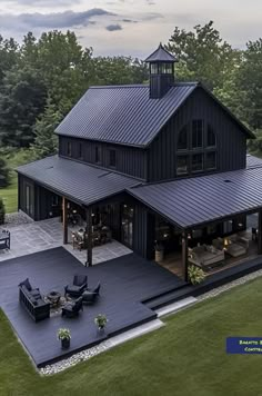 an aerial view of a large black house with a covered patio and outdoor seating area