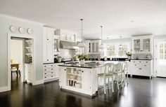 an image of a kitchen setting with white cabinets and black counter tops, along with chairs