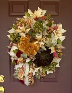 a wreath on the front door with flowers and ribbons hanging from it's sides