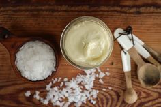 a wooden spoon with some white rice in it and a jar of cream on the table